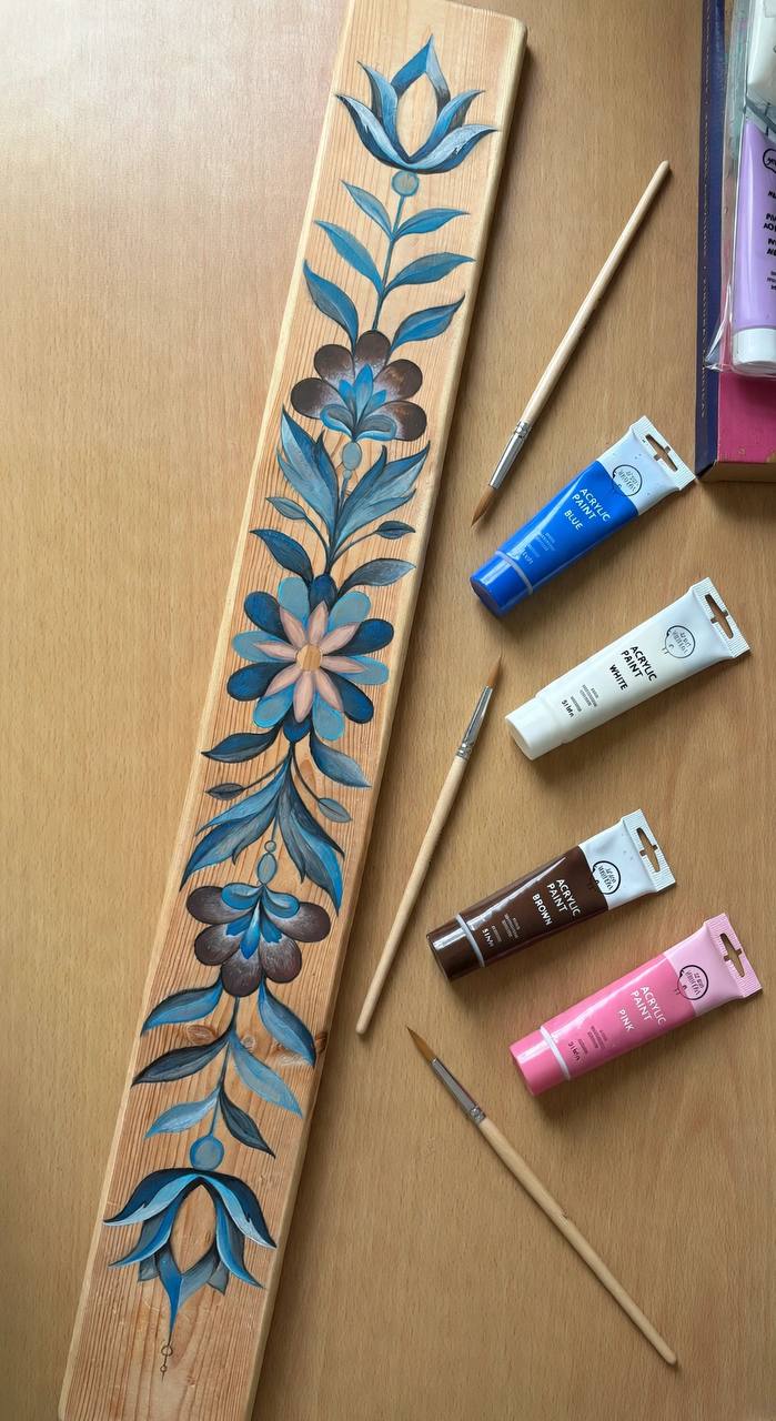 The painted timber panel on Maryam's work table with paints and brushes