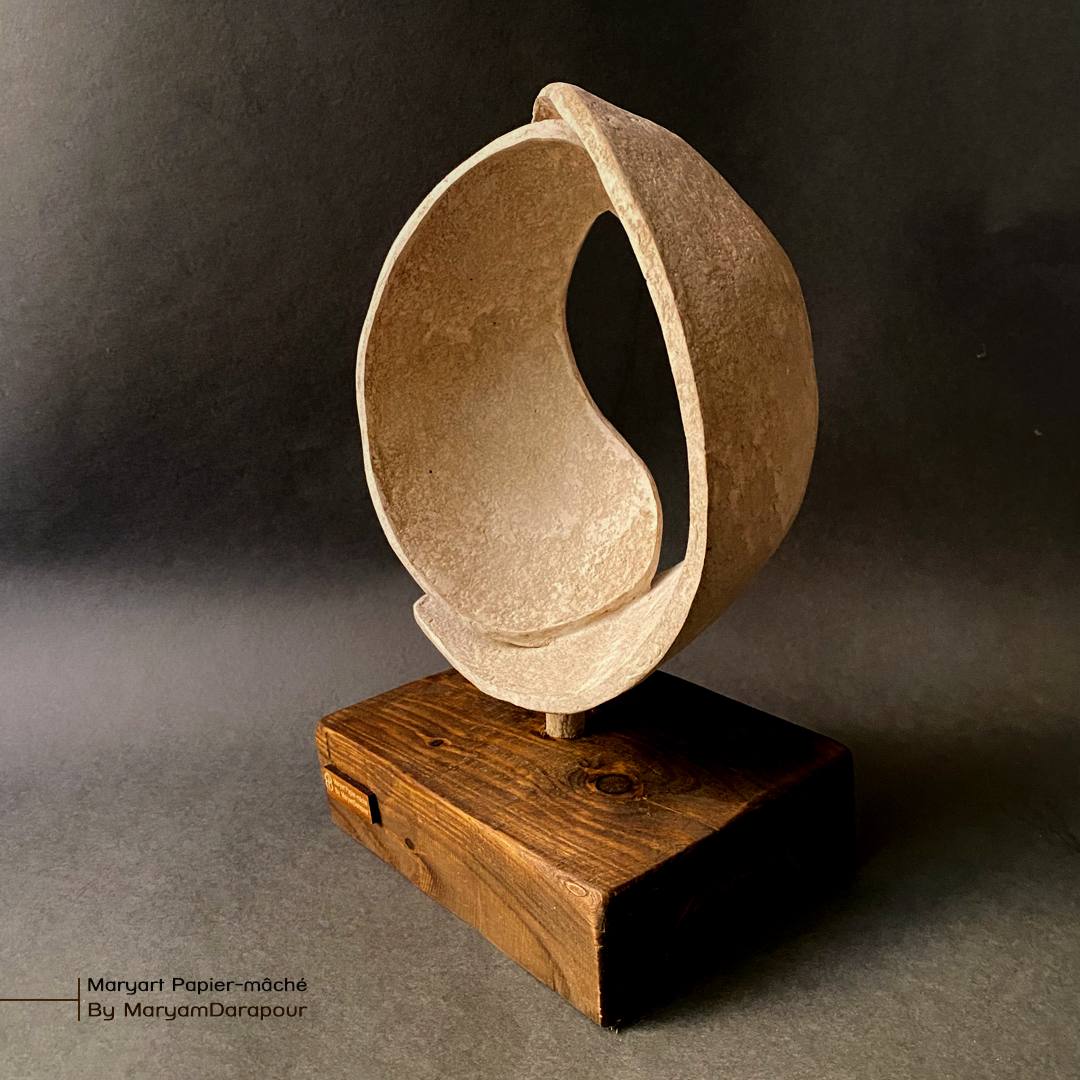 Open ring sculpture on timber block, studio photo